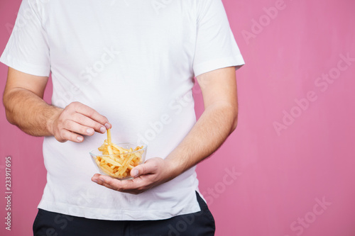 glutton man eating tasty french fries. imbalanced ration, snacking with fast food, unhealthy diet