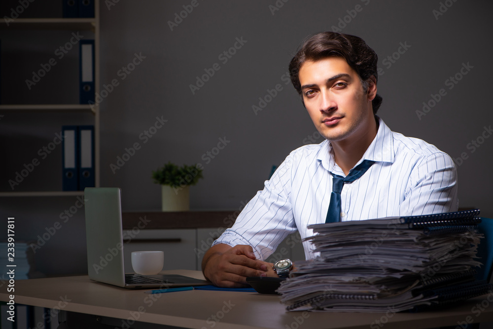 Fototapeta premium Young financial manager working late at night in office 