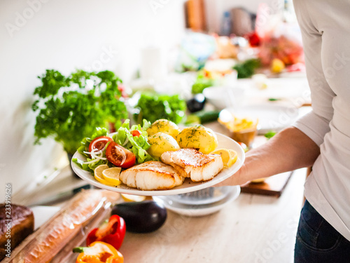 Fried fish with potatoes on white plate