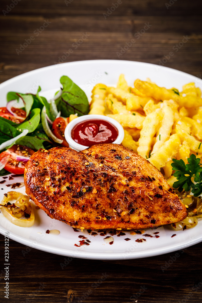 Grilled chicken fillet with french fries on wooden table Grilled chicken fillet with french fries on wooden table