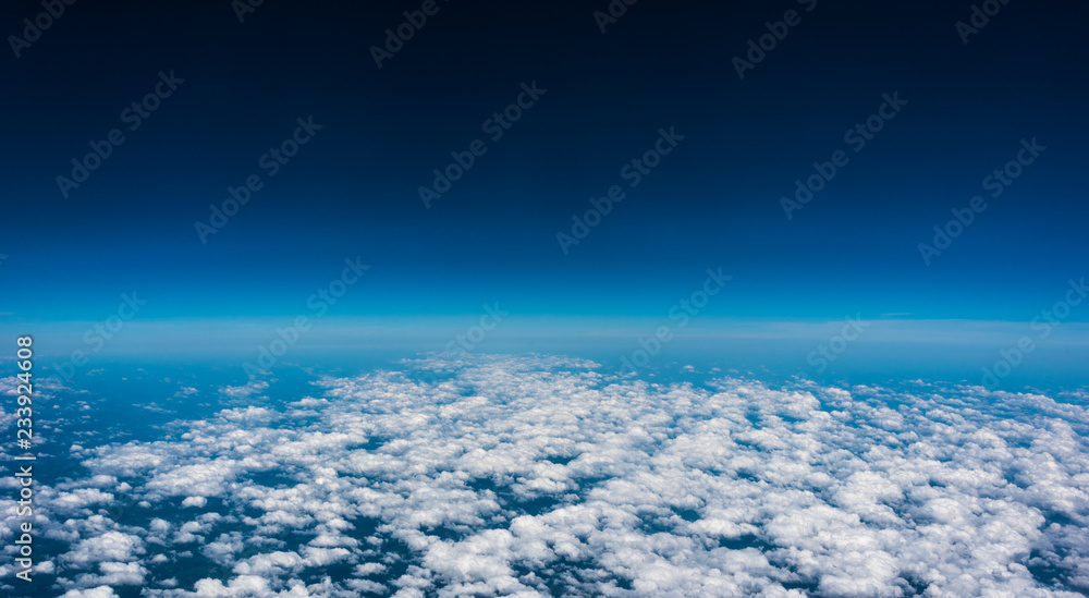 Above the clouds.  High flight and view of near edge of space at 35,000 feet.  Looking out the air plane window.
