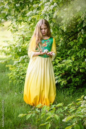 Blond young girl posing in a yellow green dress near birch trees © kuzenkova