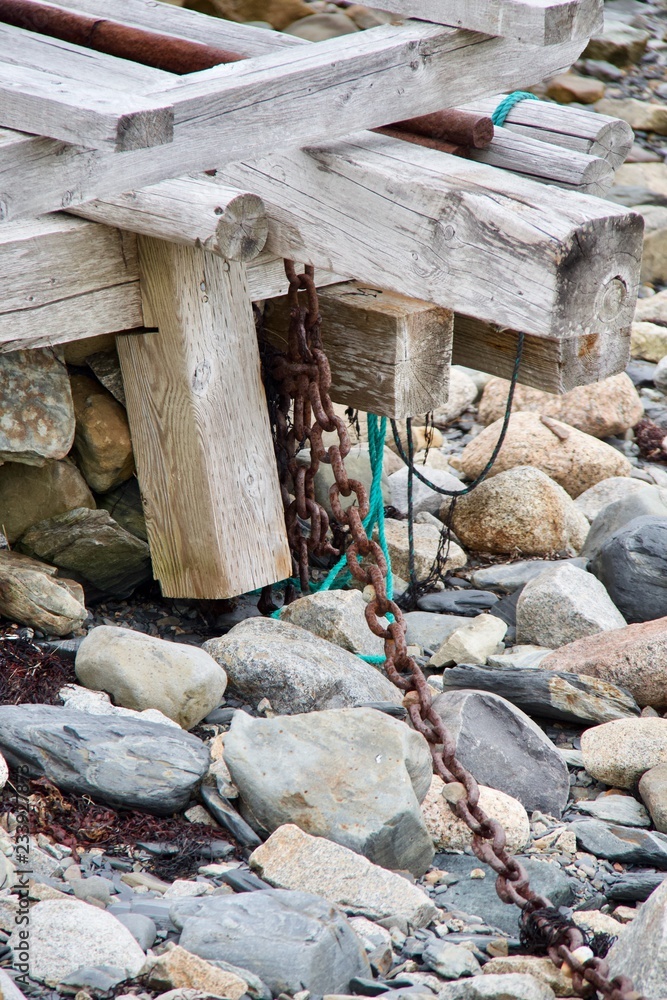 Broken wharf on a shore of beach stones.Rusty chain and bit of turquoise rope are like memories gone by. Broken wharf on a shore of beach stones.Rusty chain and bit of turquoise rope are like memories gone by.
