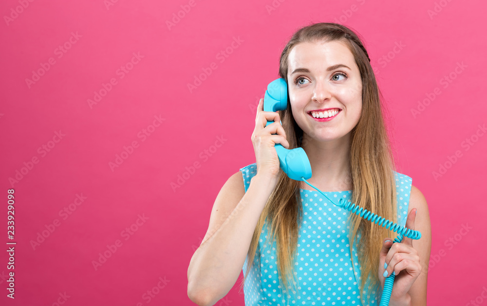 Young woman talking on an old fashioned retro phone on a pink background Young woman talking on an old fashioned retro phone on a pink background