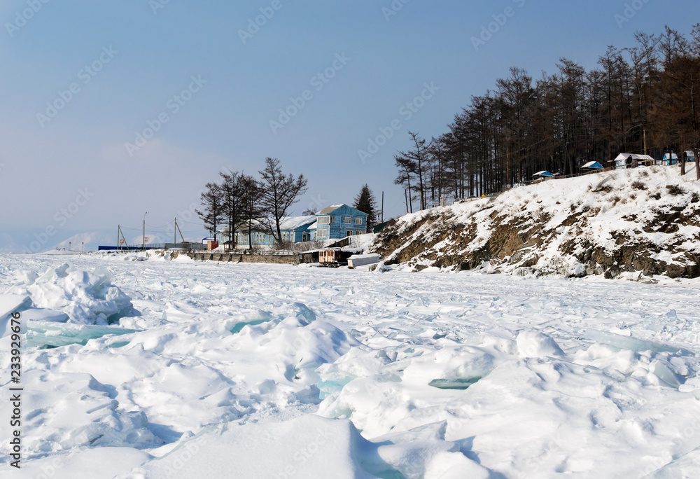 Lake Baikal in winter. Lonely blue wooden house near forest on shore. Russia