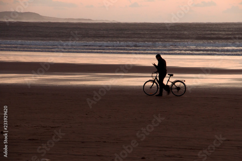 Sunset on the beach with a man and his bicycle backlit