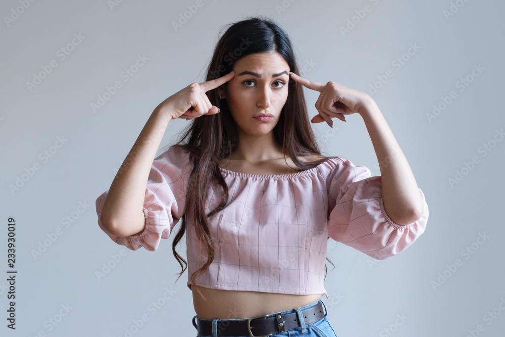 Serious young Caucasian girl touching temples with index fingers and frowning. Pretty female startuper evaluating before doing. Time to think concept Serious young Caucasian girl touching temples with index fingers and frowning. Pretty female startuper evaluating before doing. Time to think concept