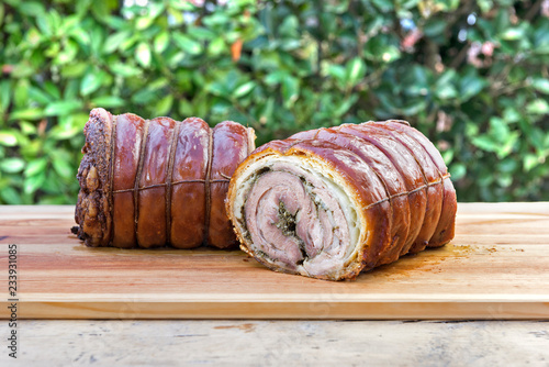 Roasted rolled pork cut in half on chopping board photo