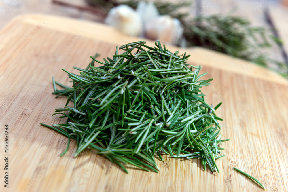 Rosemary leaves heaped on chopping board Rosemary leaves heaped on chopping board