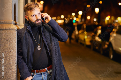 Hombre joven con barba y elegante en la calle, en una noche de invierno