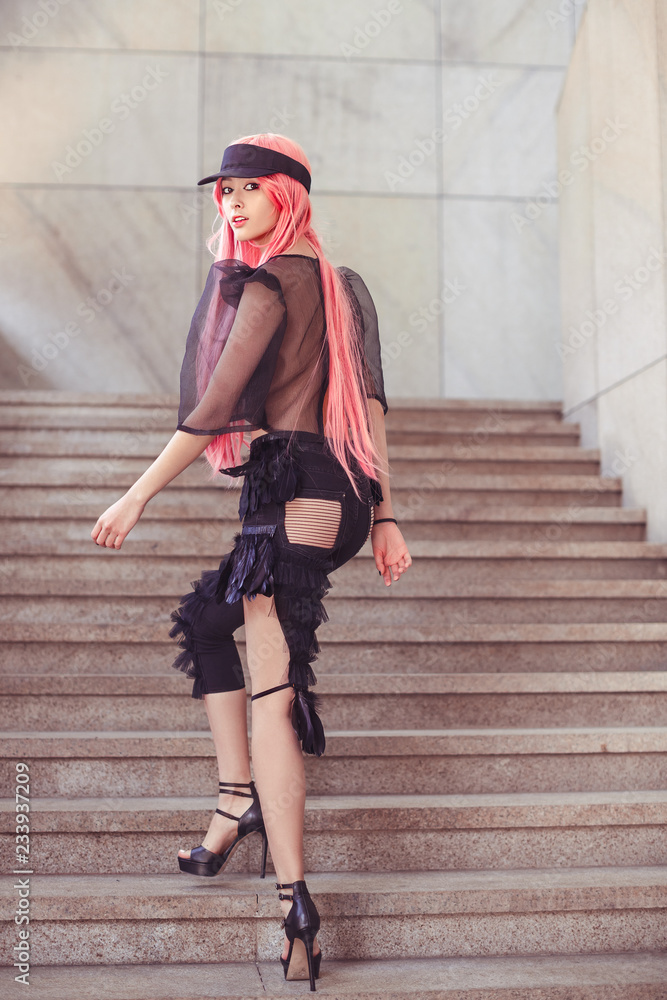 Fotka „Japan anime cosplay. Colorful portrait of young attractive asian  woman in sexy dress with creative make-up and wearing pink wig outdoors.  Trendy Japanese girl happy walking on steps and turns around“ ze