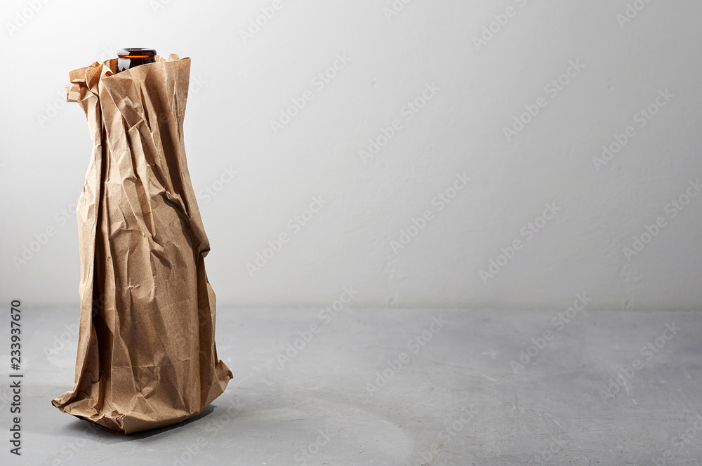 Beer bottle in the paper bag on gray concrete background