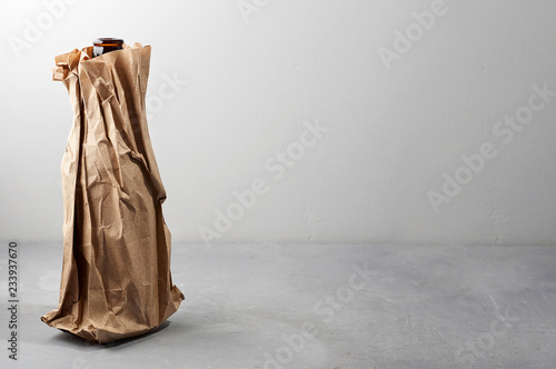 Obraz na płótnie Beer bottle in the paper bag on gray concrete background w salonie