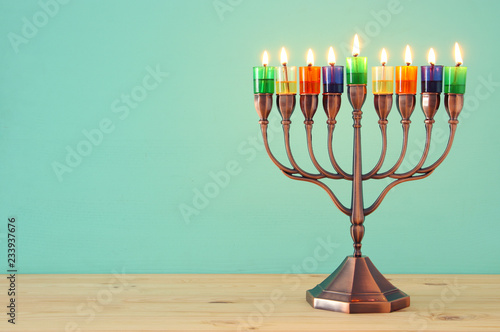 image of jewish holiday Hanukkah background with menorah (traditional candelabra) and colorful oil candles.