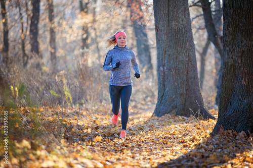 Fototapeta Naklejka Na Ścianę i Meble -  Young woman jogging on trail in autumn park