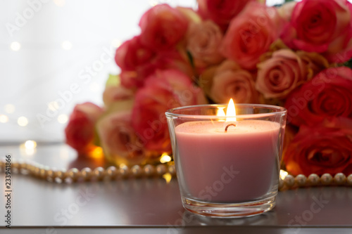 Burning candles with rose fresh flowers bouquet on gray table  close up home interior details