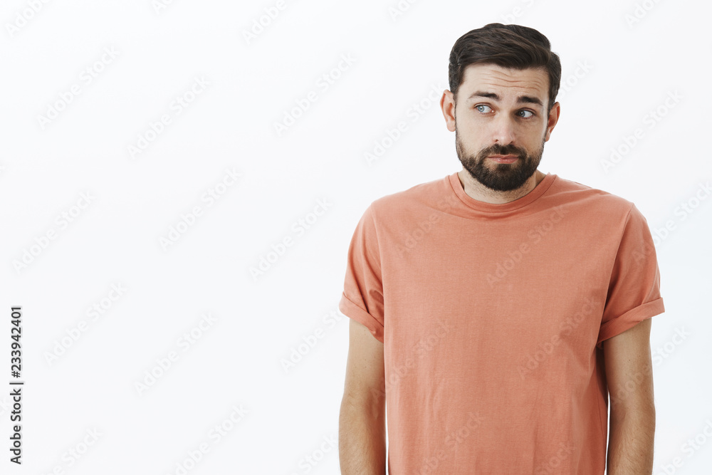 Guilty and shy male coworker being shouted at hiding eyes, looking left, stooping, making slight shug and raising eyebrows insecure and clueless, feeling sorry posing unconfident over gray background Guilty and shy male coworker being shouted at hiding eyes, looking left, stooping, making slight shug and raising eyebrows insecure and clueless, feeling sorry posing unconfident over gray background