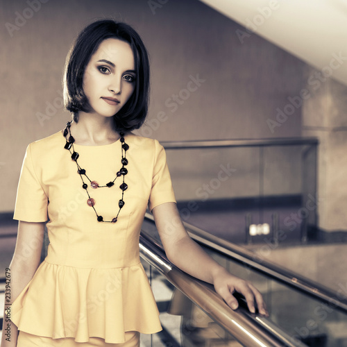 Young fashion business woman in yellow peplum dress at office photo