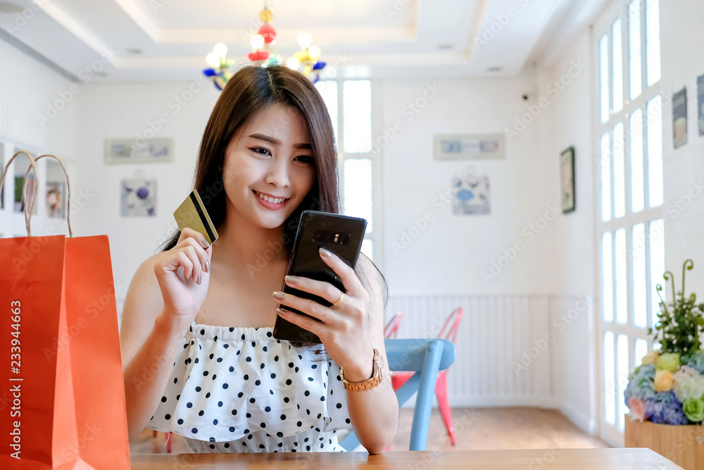 Young woman holding credit card and and using smartphone. Shopping online Young woman holding credit card and and using smartphone. Shopping online