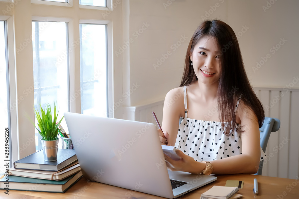 Beautiful Young woman working on laptop and computer at home
