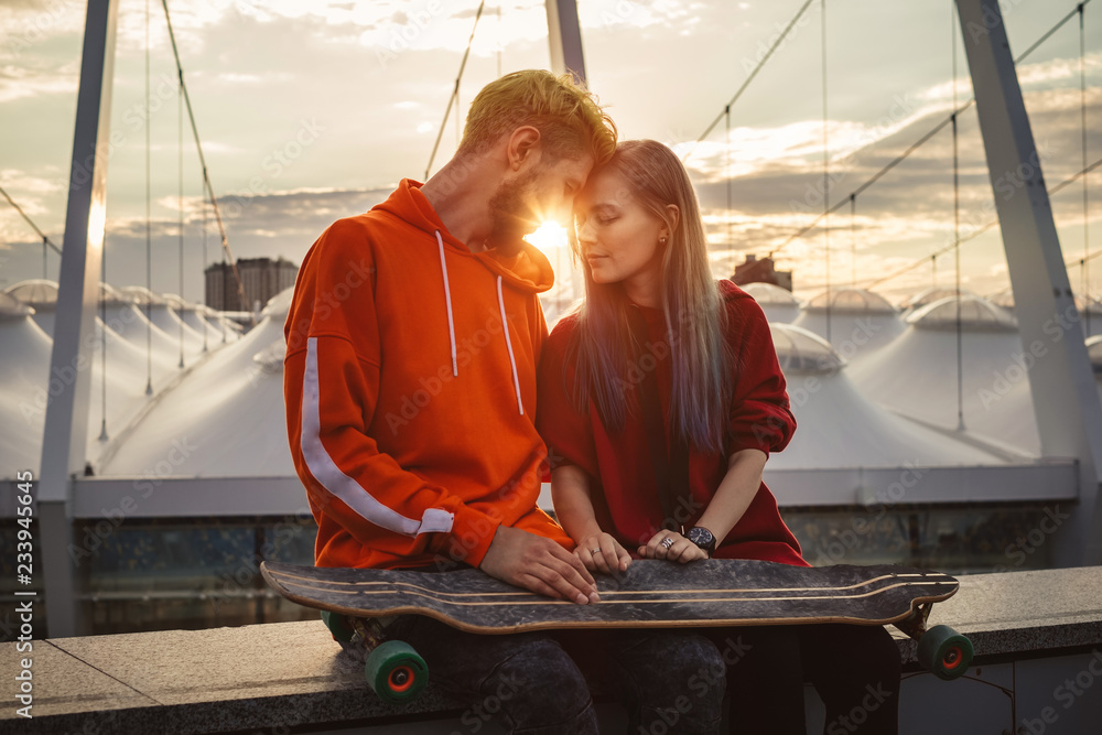 Young hipster couple enjoying city sunset on the roof