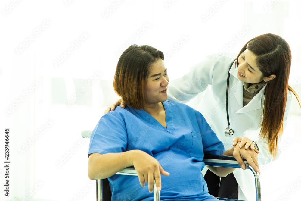 Mature obstetrician gynecologist riding pregnant woman on wheelchair at maternity hospital. Health care and empathy concept. Mature obstetrician gynecologist riding pregnant woman on wheelchair at maternity hospital. Health care and empathy concept.