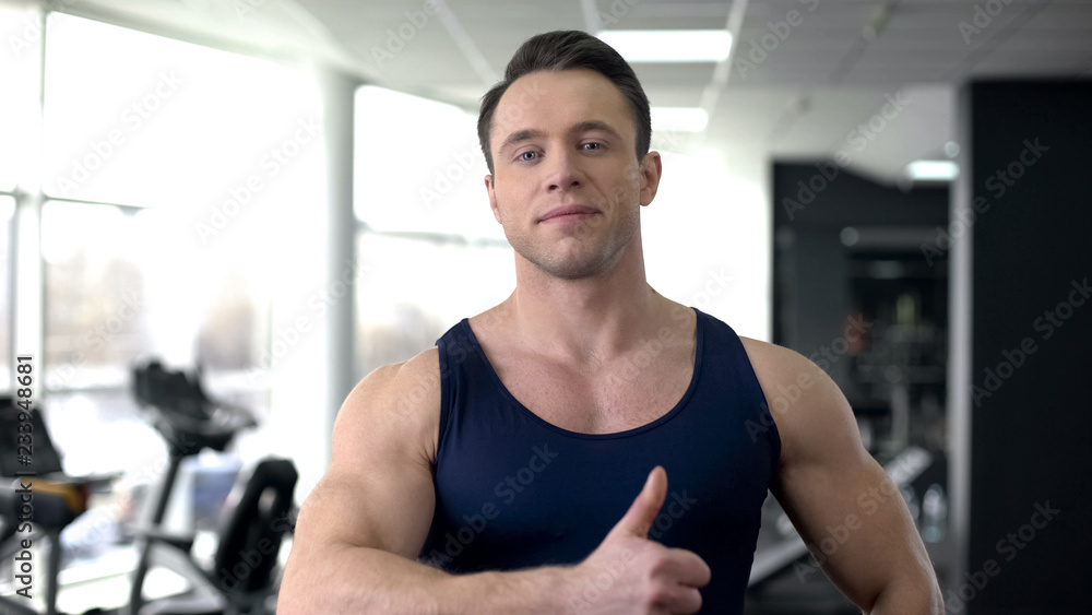 Athlete male showing thumbs up, workout in gym, sport results, healthy lifestyle Athlete male showing thumbs up, workout in gym, sport results, healthy lifestyle