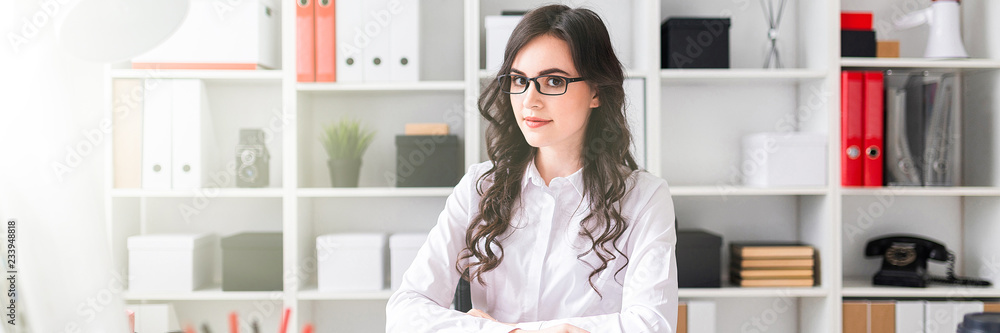 Beautiful young girl is sitting at the table in the office. Beautiful young girl is sitting at the table in the office.