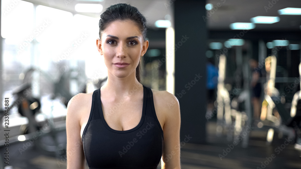 Fototapeta premium Portrait of confident young woman in gym looking into camera, personal trainer