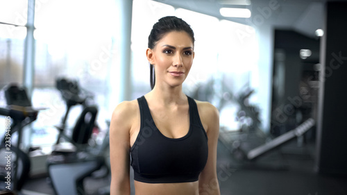 Athletic fitness woman in gym looking at camera, active lifestyle, sport club