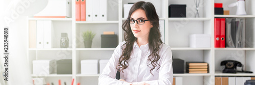 Beautiful young girl is sitting at the table in the office.