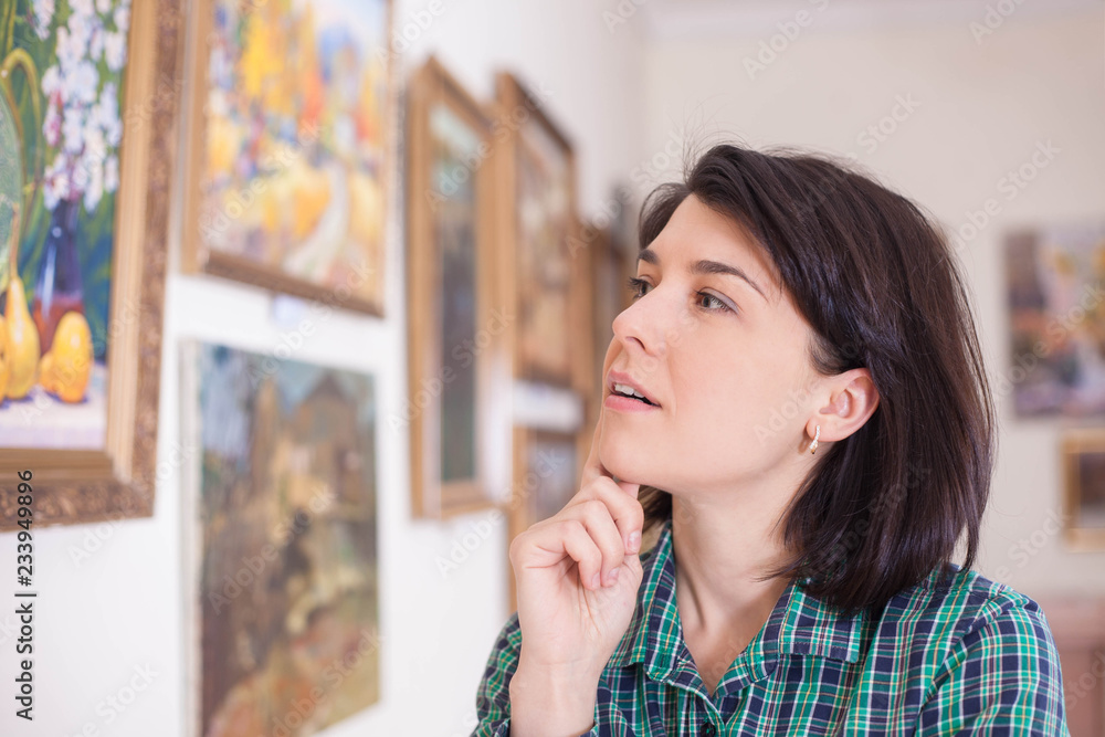 Portrait of a young woman looking at a painting in an art gallery or museum.