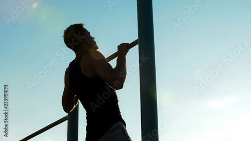 Strong man performing exercises on the uneven bars, sport and healthy lifestyle