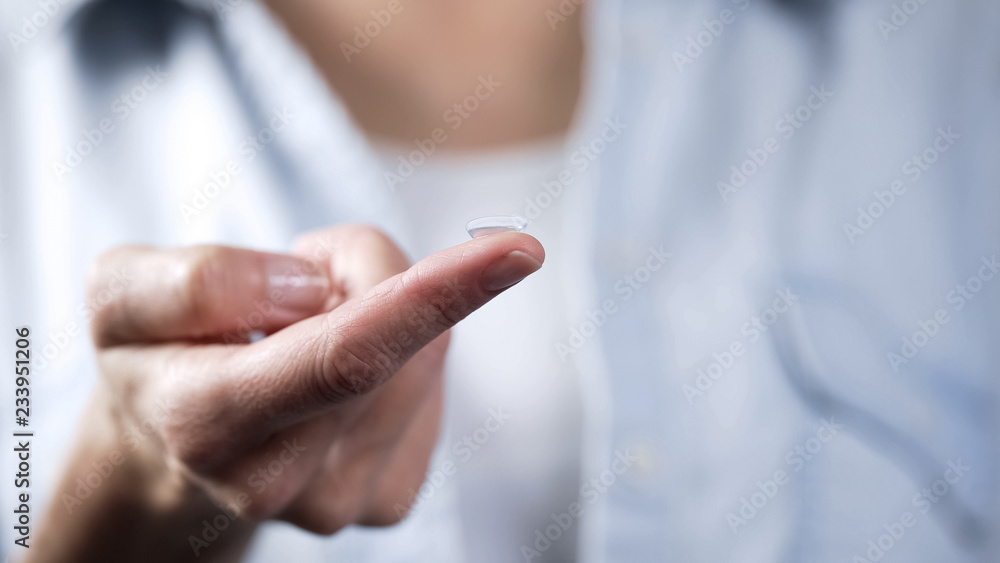 Female preparing contact lens to put in her eye, ophthalmology and vision