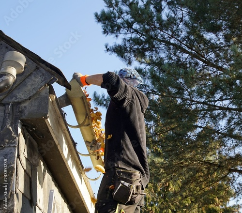 Dachdecker demontiert eine alte Dachrinne photo