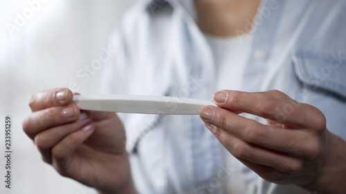 Woman holding pregnancy test in hands, looking at result, gynecology close-up