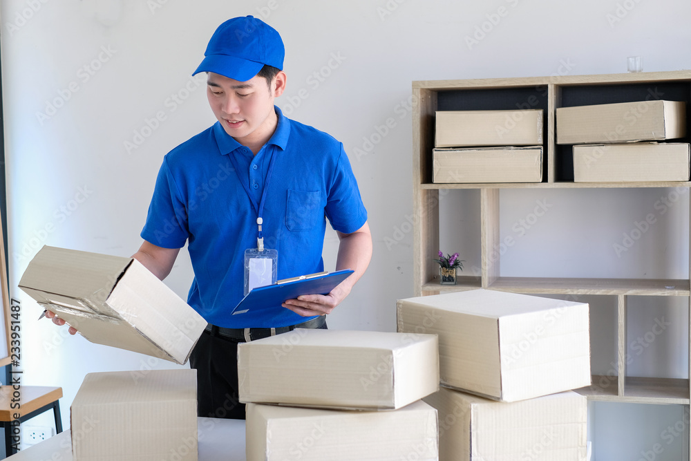 Young delivery man check the box before sending product. Young delivery man check the box before sending product.