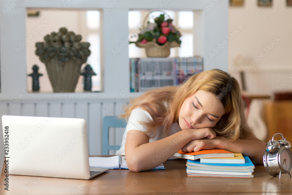 Female student who fell asleep on the desk in the library with a pile of books. Female student who fell asleep on the desk in the library with a pile of books.