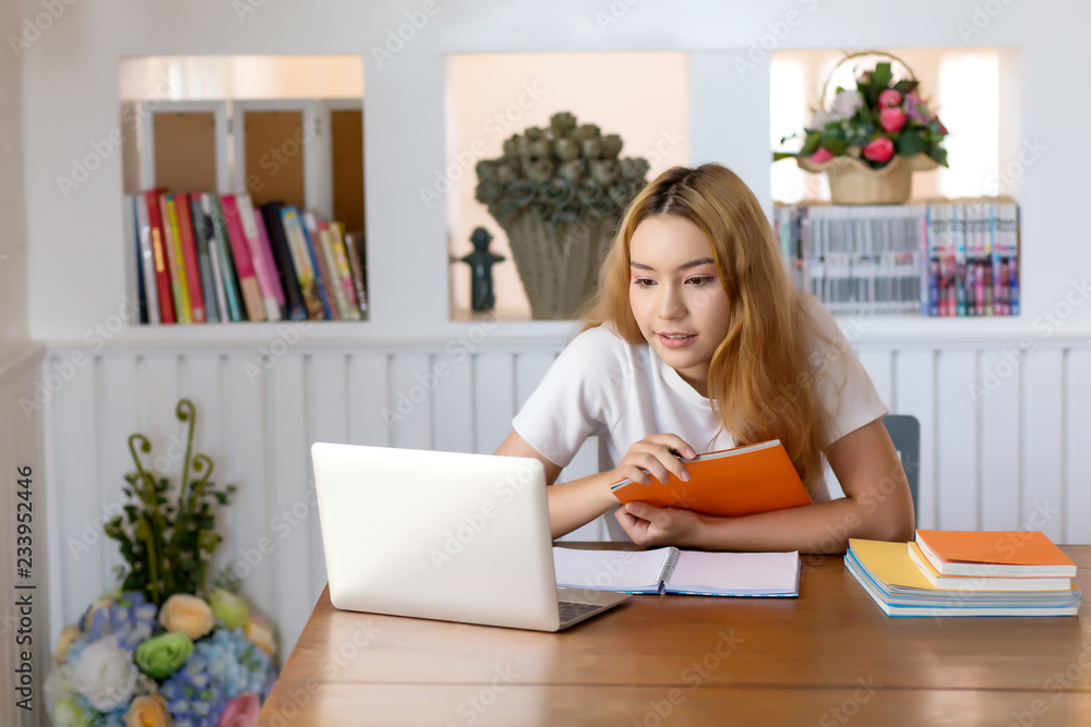 Young woman student working on laptop sitting in library at home Young woman student working on laptop sitting in library at home