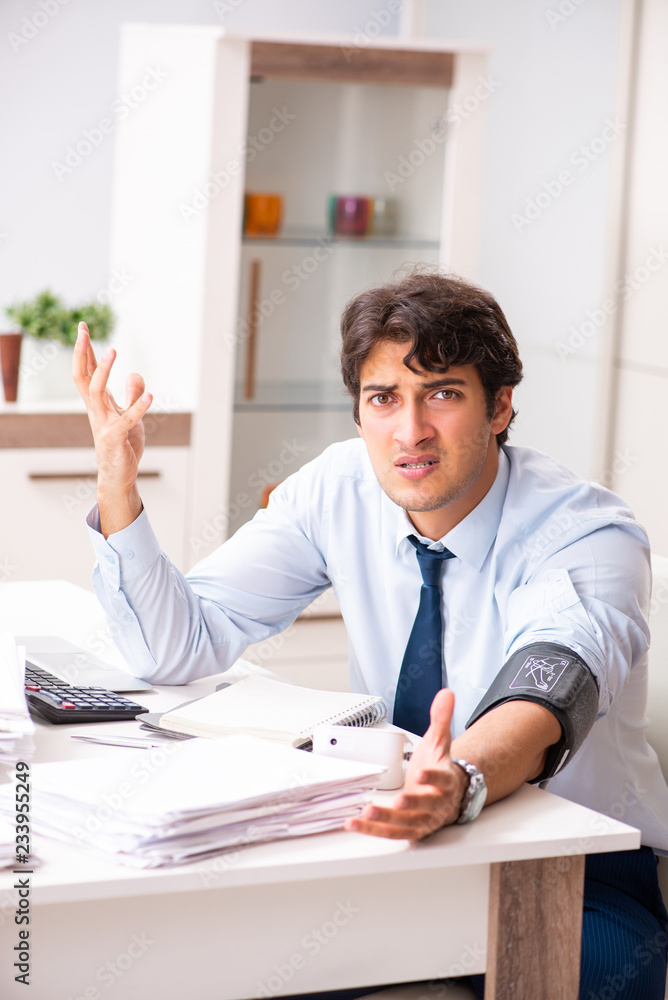 Man under stress measuring his blood pressure Man under stress measuring his blood pressure