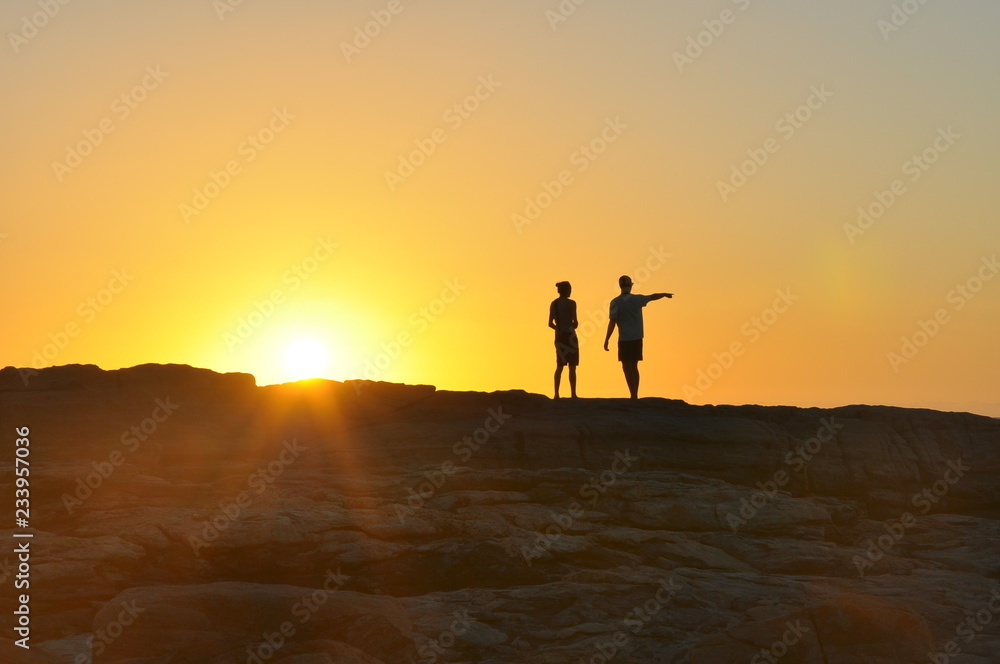 Two guys on a cliff at sunset