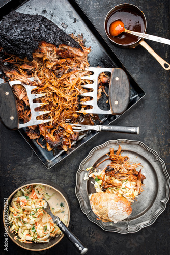 Traditional barbecue pulled pork piece of Bosten butt torn to bits with coleslaw and burger as top view on a board photo