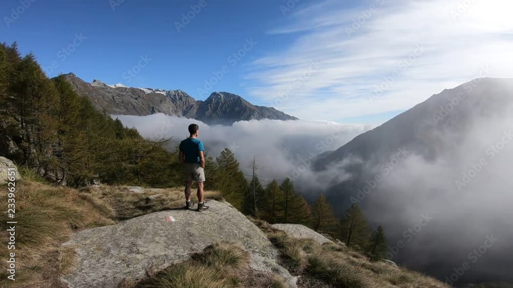 Man on the mountains looking at landscape over the clouds, Gran Paradiso National Park, Italy Man on the mountains looking at landscape over the clouds, Gran Paradiso National Park, Italy