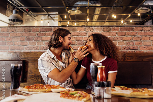 Smiling couple feeding each other pizza
