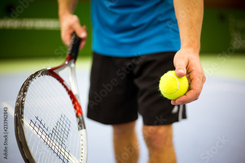Close-up of male hand holding tennis ball and racket, professional tennis player starting set in the tennis hall © Khaligo