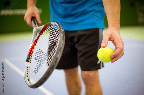 Close-up of male hand holding tennis ball and racket, professional tennis player starting set in the tennis hall