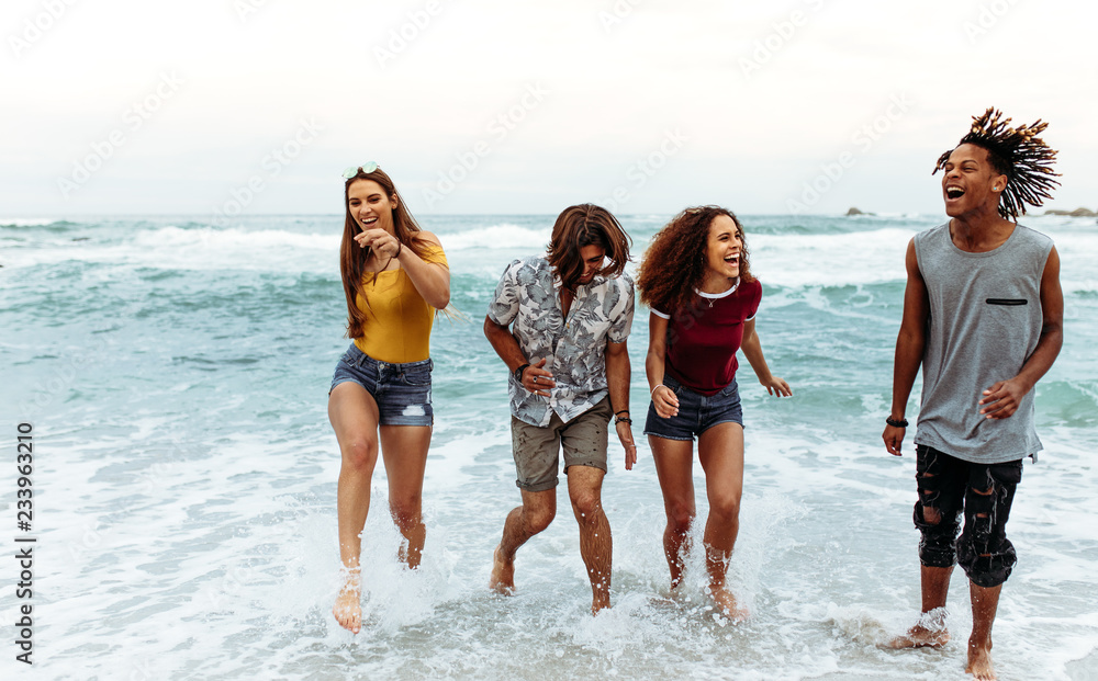 Cheerful young friends walking out of sea water Cheerful young friends walking out of sea water