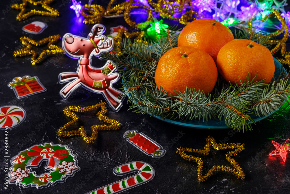 Christmas mood, deer, holiday decor, pine branches and tangerines on dark background.