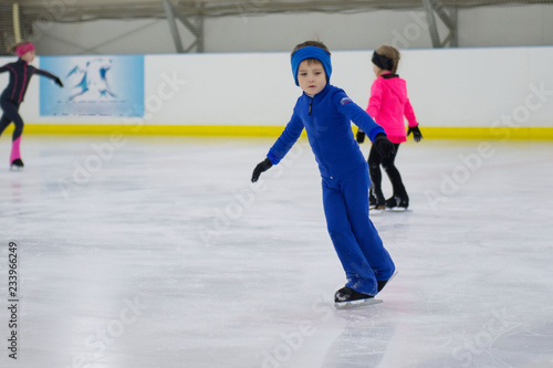 Little boy learning to ice skate. Figure skating school. Young figure skaters practicing at indoor skating rink.