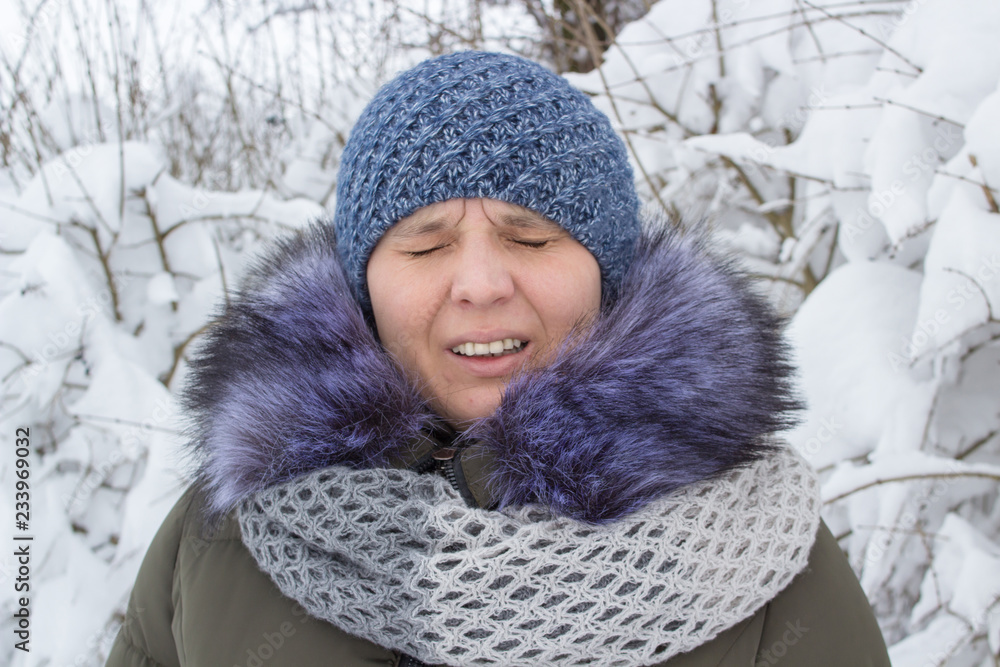 sneezing woman in the winter,young woman sneezes in the park in winter sneezing woman in the winter,young woman sneezes in the park in winter